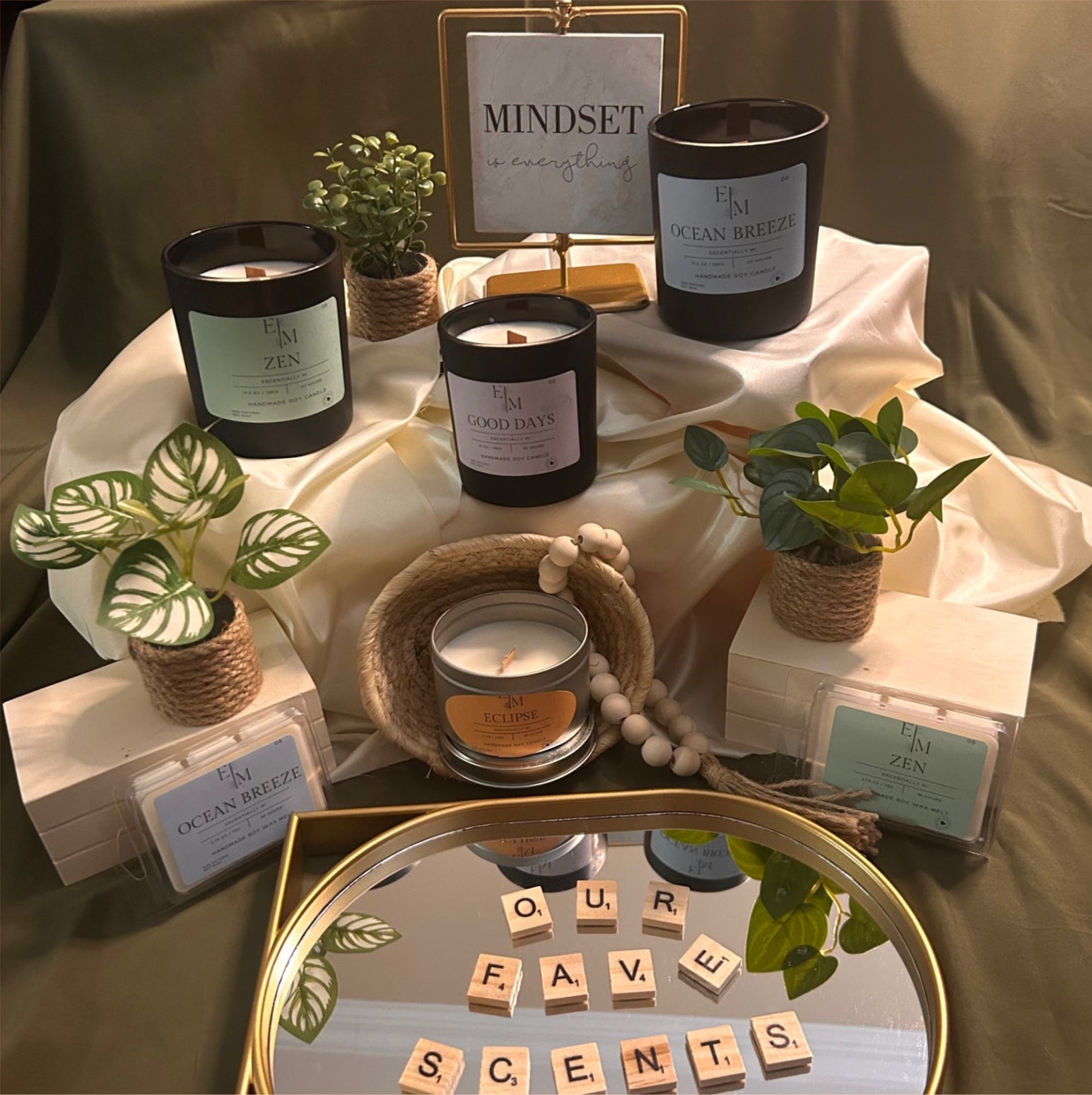 Tabletop display with candles, plants, and decorative items on a neutral background